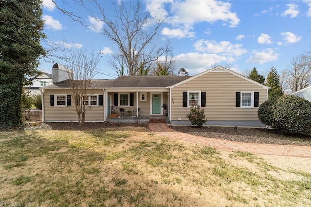 ranch-style home featuring covered porch, a chimney, and a front lawn