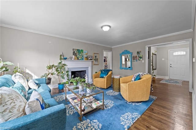 living room with ornamental molding, a fireplace, baseboards, and wood finished floors