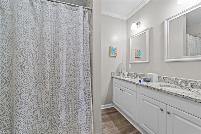 bathroom featuring ornamental molding, wood finished floors, a sink, and double vanity