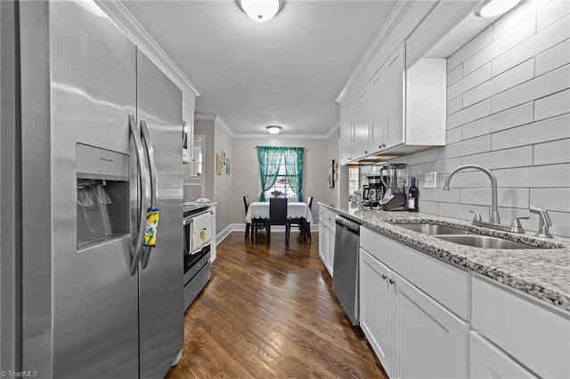 kitchen featuring dark wood finished floors, stainless steel appliances, ornamental molding, white cabinets, and a sink