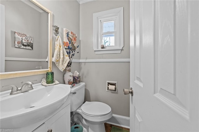 half bathroom featuring toilet, baseboards, and vanity