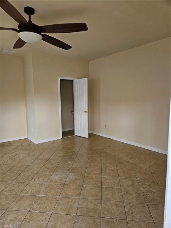 tiled spare room featuring ceiling fan and baseboards