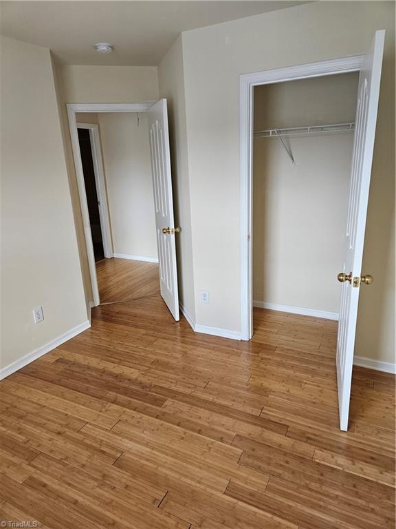 unfurnished bedroom with light wood-style floors, a closet, and baseboards