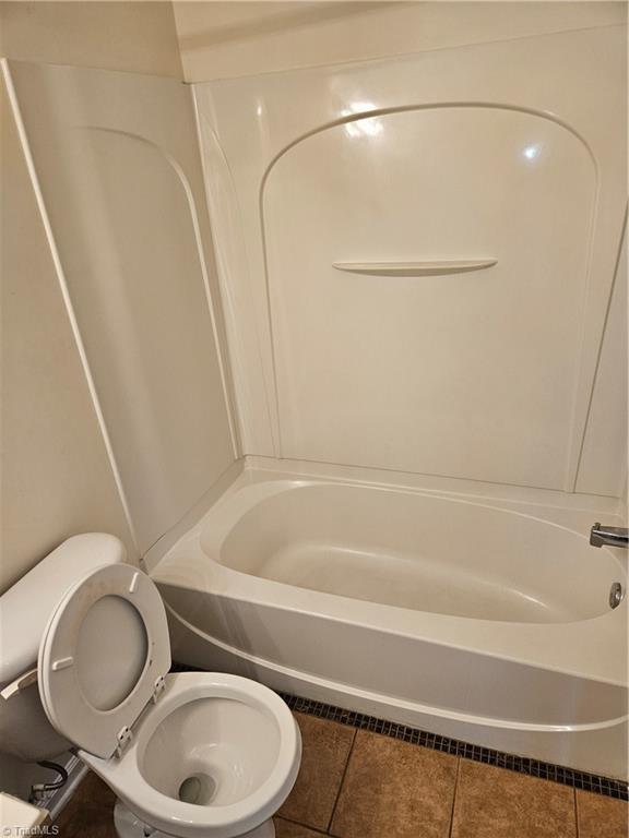 bathroom with toilet,  shower combination, and tile patterned flooring