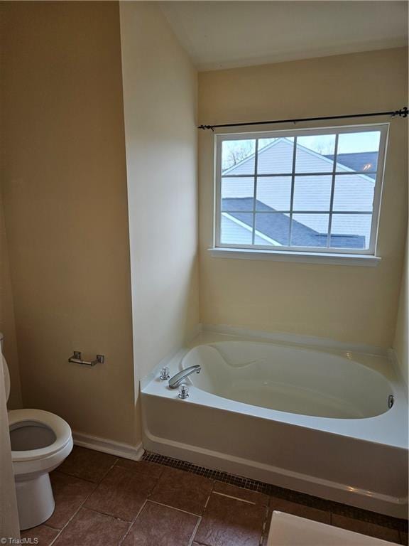 bathroom with a bath, tile patterned floors, toilet, and baseboards