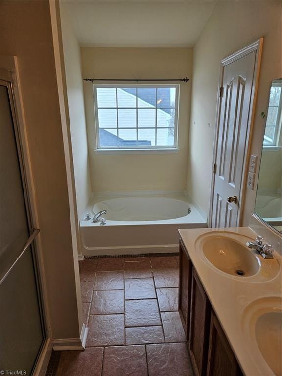 bathroom featuring double vanity, a bath, and a sink