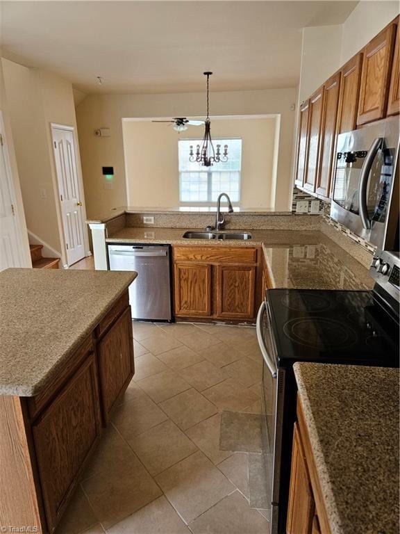 kitchen with brown cabinetry, a peninsula, stainless steel appliances, and a sink