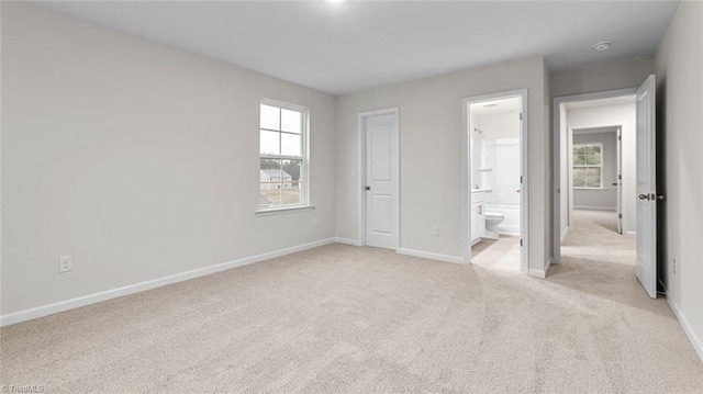 unfurnished bedroom featuring ensuite bath and light colored carpet