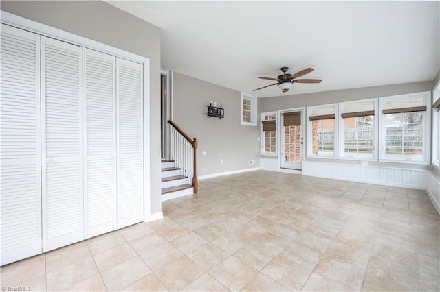 unfurnished living room with light tile patterned floors, stairway, baseboards, and ceiling fan