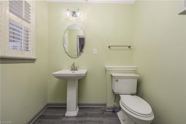 half bathroom with toilet, wood finished floors, and baseboards