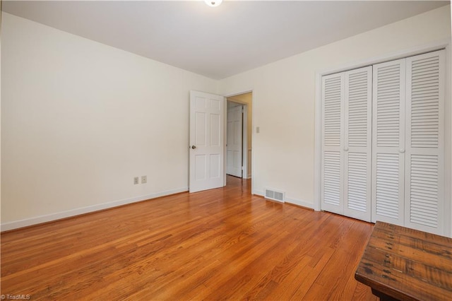 unfurnished bedroom featuring visible vents, baseboards, a closet, and light wood-style flooring