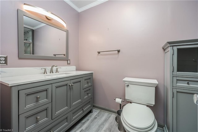 bathroom featuring toilet, ornamental molding, wood finished floors, baseboards, and vanity