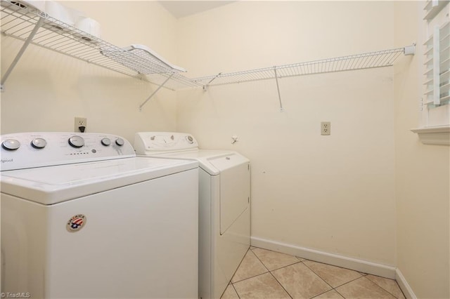 washroom featuring light tile patterned floors, baseboards, washing machine and dryer, and laundry area