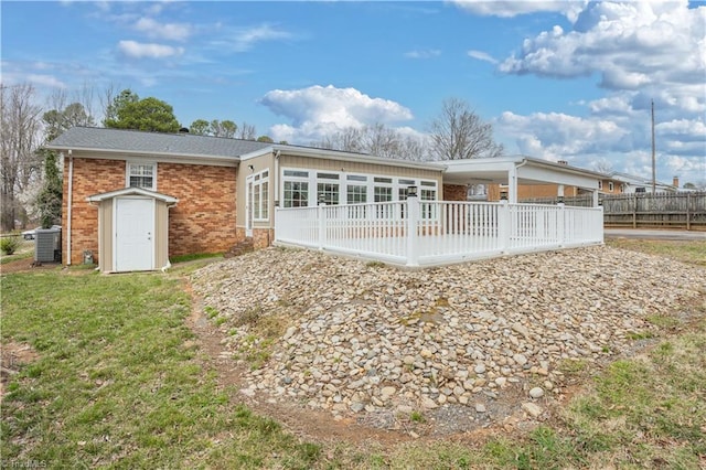 back of property featuring a yard, central air condition unit, brick siding, and fence