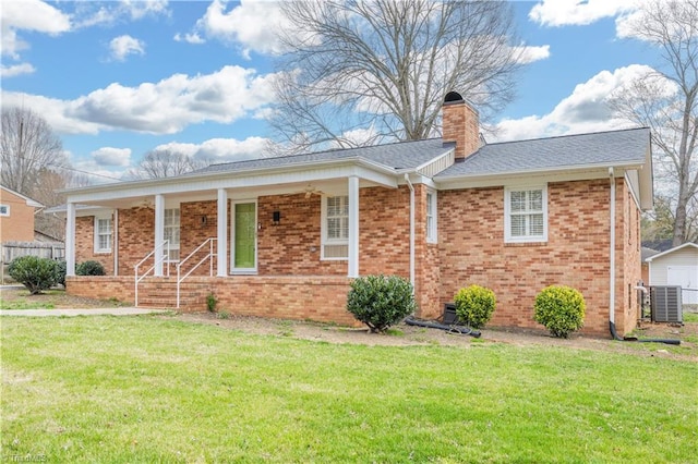 ranch-style home featuring a chimney, brick siding, covered porch, and a front yard