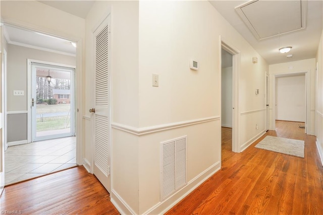 corridor featuring visible vents, baseboards, attic access, and wood finished floors