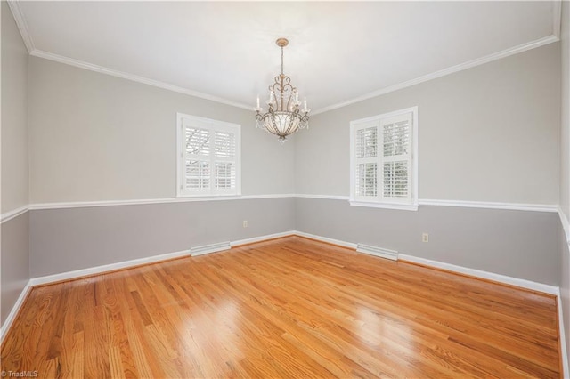 empty room with a notable chandelier, visible vents, light wood-type flooring, and baseboards