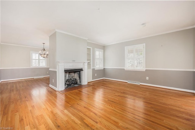 unfurnished living room featuring a fireplace, an inviting chandelier, light wood-style floors, and baseboards