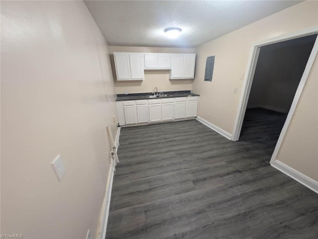 kitchen with a textured ceiling, dark hardwood / wood-style floors, white cabinetry, and sink