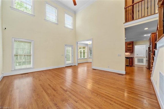 1010 Mill Pointe Way, Elon, NC 27244 - unfurnished living room featuring ornamental molding, a towering ceiling, light wood-style flooring, ceiling fan, and healthy amount of natural light