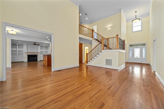 1010 Mill Pointe Way, Elon, NC 27244 - unfurnished living room featuring a high ceiling, crown molding, light wood-type flooring, a ceiling fan, and a fireplace