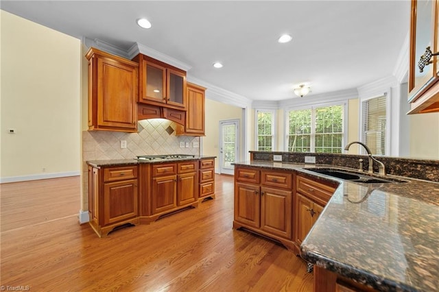 1010 Mill Pointe Way, Elon, NC 27244 - kitchen with light wood finished floors, brown cabinets, decorative backsplash, stainless steel gas cooktop, and ornamental molding