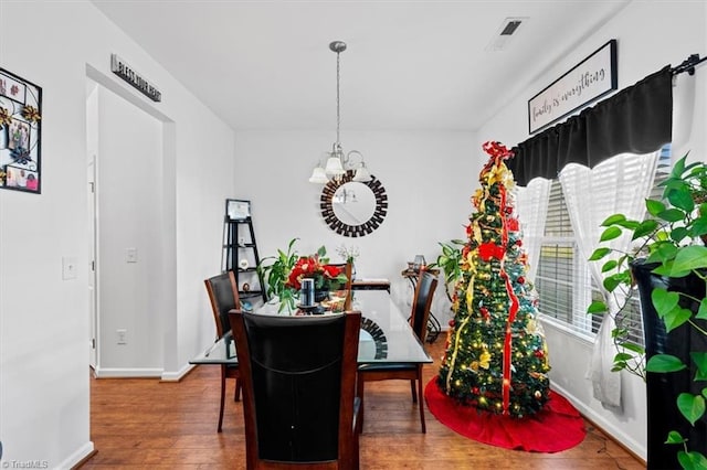 dining area with hardwood / wood-style floors and a notable chandelier