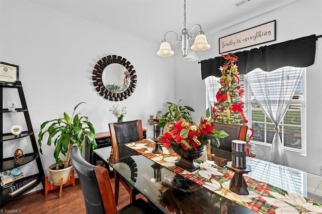 dining room with wood-type flooring and an inviting chandelier