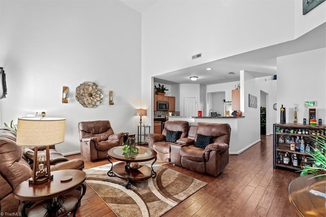 living room featuring a towering ceiling and dark hardwood / wood-style floors