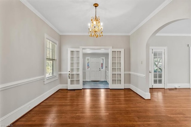 foyer entrance with plenty of natural light, wood finished floors, arched walkways, and baseboards