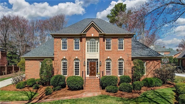 georgian-style home with brick siding and roof with shingles