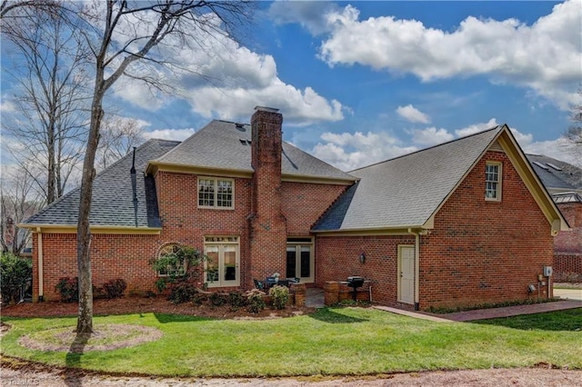 rear view of house with a yard, brick siding, a chimney, and a shingled roof