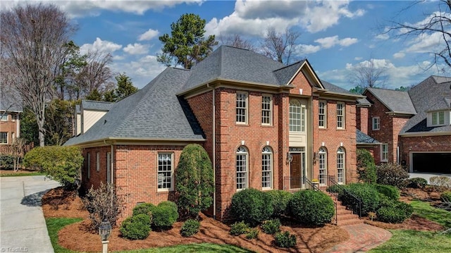 view of front of property featuring concrete driveway, brick siding, and a shingled roof