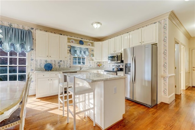 kitchen featuring light wood-style flooring, light stone counters, a kitchen island, appliances with stainless steel finishes, and decorative backsplash