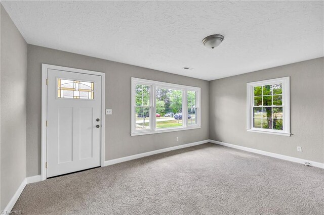 foyer featuring a textured ceiling and carpet floors