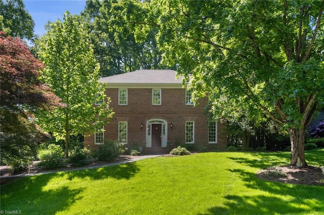 colonial home featuring brick siding and a front yard