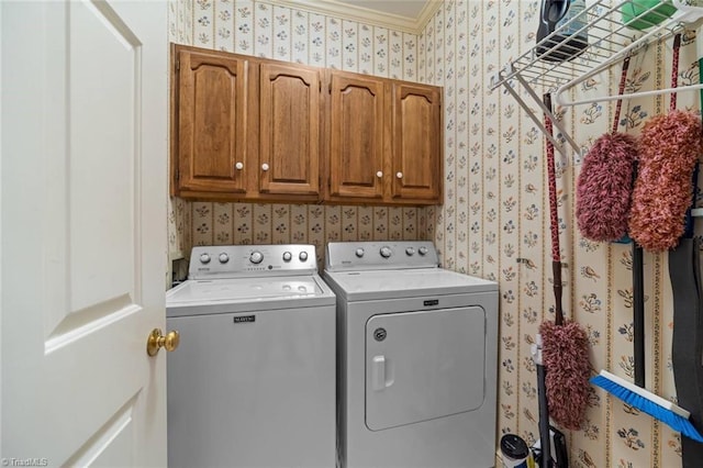 laundry area with ornamental molding, cabinet space, washing machine and dryer, and wallpapered walls