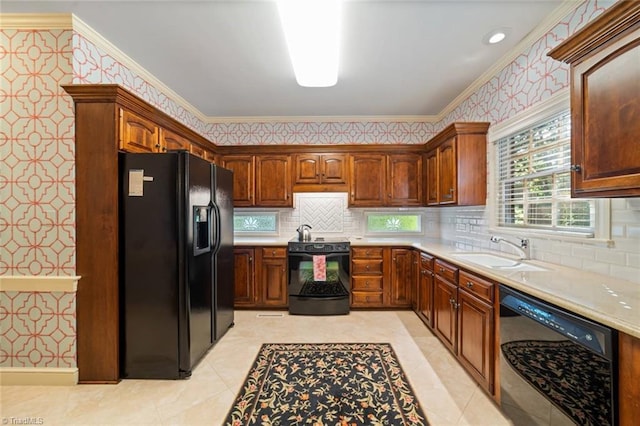kitchen featuring ornamental molding, wallpapered walls, light countertops, a sink, and black appliances