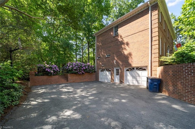 view of property exterior featuring brick siding, a garage, and driveway
