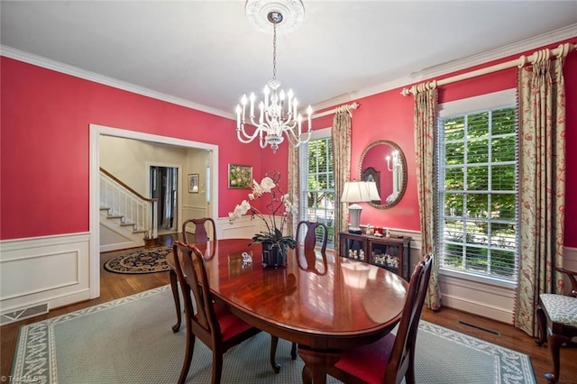 dining room featuring wainscoting, a chandelier, visible vents, ornamental molding, and stairway