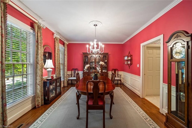 dining space featuring a wealth of natural light, ornamental molding, wood finished floors, and a notable chandelier