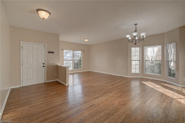 foyer entrance with a textured ceiling, a notable chandelier, and dark hardwood / wood-style flooring