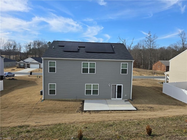 rear view of house with a patio area, fence, and solar panels