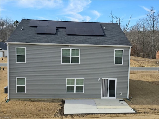 back of house featuring roof mounted solar panels, central AC unit, and a patio