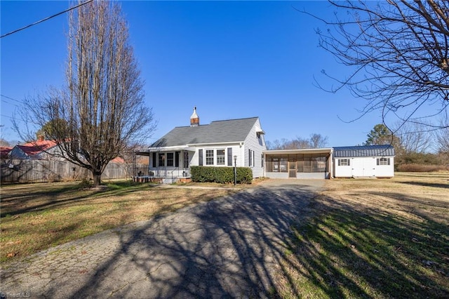 cape cod home with a carport, a porch, an outdoor structure, and a front yard