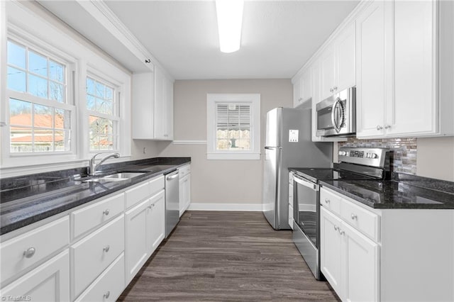 kitchen with white cabinets, appliances with stainless steel finishes, dark stone countertops, and sink