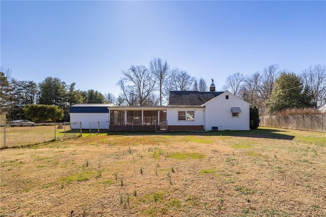 back of house with a sunroom and a lawn