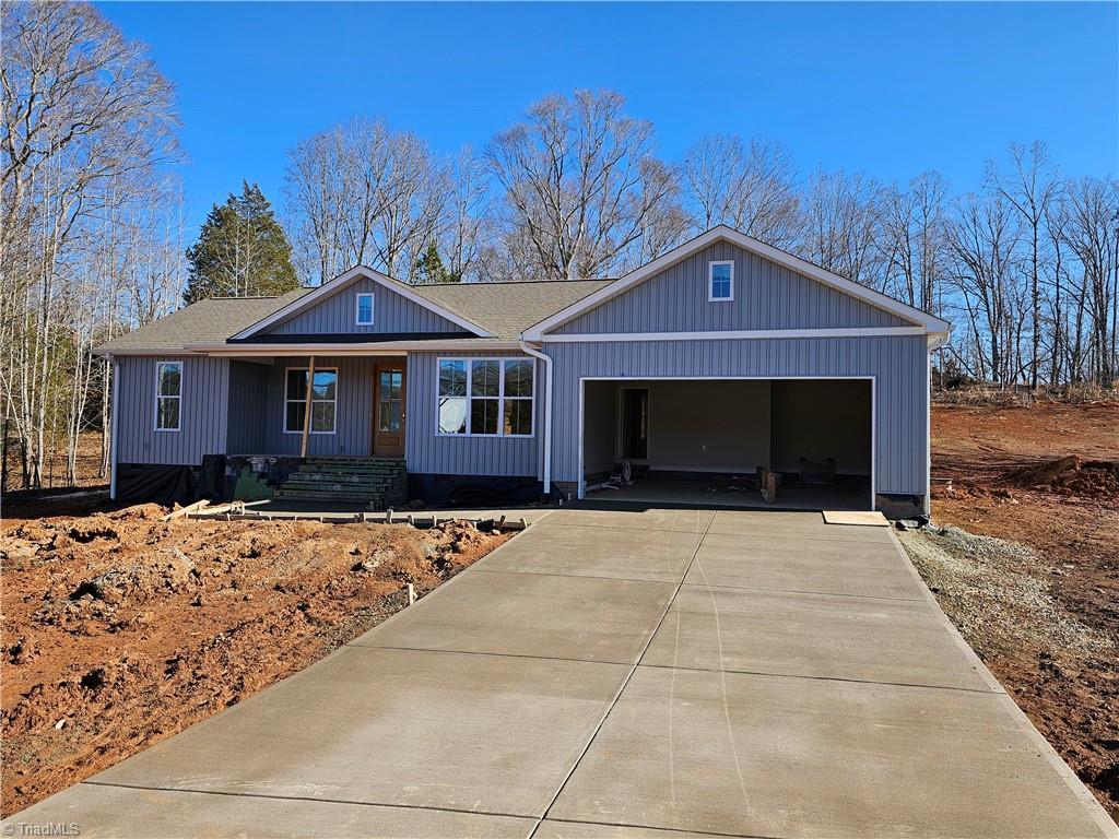 ranch-style house with a garage, a shingled roof, and concrete driveway