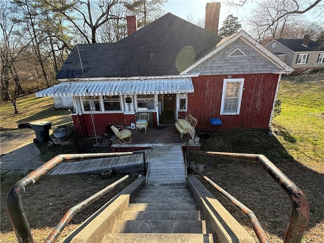 back of property with roof with shingles and a chimney