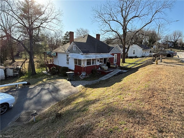 view of front of home with driveway, a front lawn, and a chimney